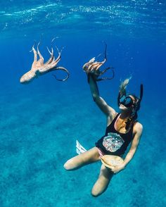 a woman is swimming in the ocean with two deer heads above her head, and another animal behind her