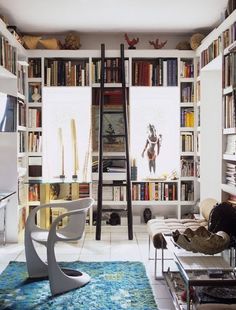 a living room filled with lots of books and furniture next to a tall book shelf