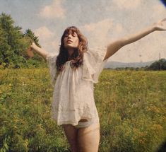 a woman standing in a field with her arms outstretched