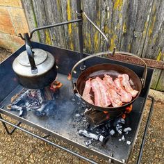 there is a frying pan with bacon cooking on the stove top next to an open fire