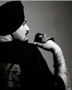 a black and white photo of a man in a beanie holding his hand up to his face