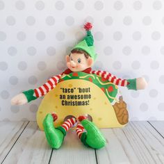 an elf holding a sign that says, taco'bout an awesome christmas