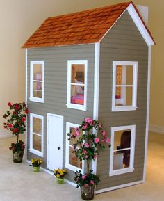 a doll house with flowers and potted plants on the floor in front of it