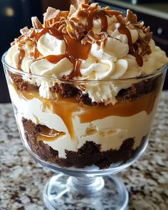 a dessert in a glass dish with caramel drizzle and whipped cream on top