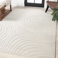 a large white rug with wavy lines on the floor in front of a black door