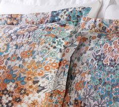 a bed with an orange and blue flowered comforter