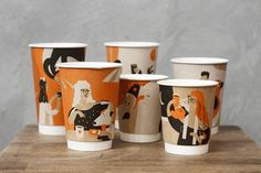 six cups with different designs on them sitting on a table next to each other,