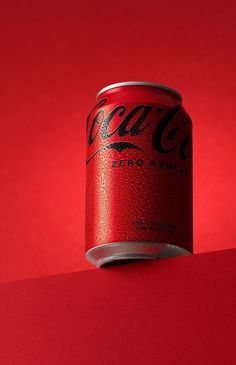 a can of coca cola sitting on top of a red surface