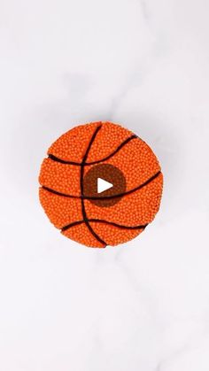 an orange basketball on a white surface with a play button in the center that is made out of beads