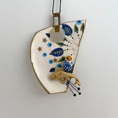 a ceramic ornament with an owl on it's back hanging from a cord