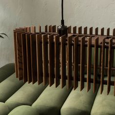 a lamp that is on top of a green couch in front of a white wall