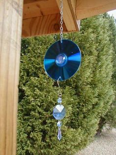 a wind chime hanging from the side of a wooden structure next to a bush