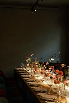 a long table is set with plates and flowers in vases on the top, along with other place settings