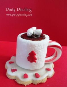 a white cup filled with marshmallows on top of a red and white plate