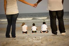 a family sitting on the beach holding hands