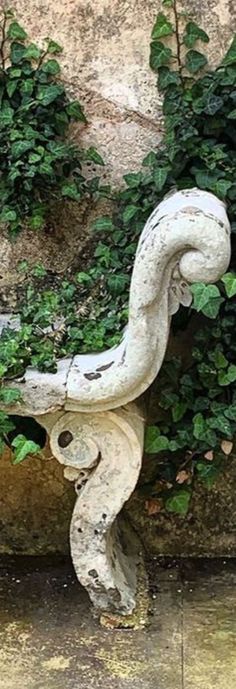 a white snake statue sitting on top of a cement wall next to green plants and bushes