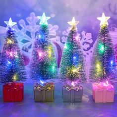 three small christmas trees with colorful lights and presents in front of snowflakes