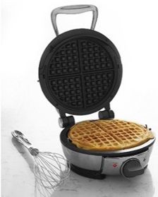 an electric waffle maker on a white counter top next to a whisk