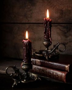 two lit candles sitting on top of an old book