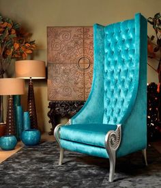 a blue chair sitting on top of a rug in front of a table with lamps