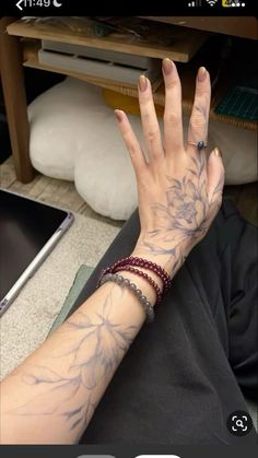 a woman's hand with tattoos on it and a laptop in front of her