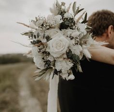 a bride and groom embracing each other in the middle of a field with white flowers