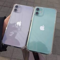 two iphones that are sitting next to each other on a street side with people holding their cell phones