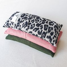 three pillows are stacked on top of each other, one pink and the other green