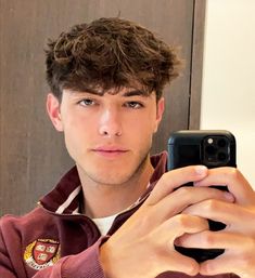 a young man taking a selfie in front of a mirror with his cell phone