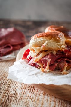 a sandwich with meat and cheese sitting on wax paper