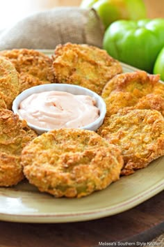 some fried food is on a plate with ranch dip and green apples in the background