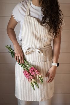 a woman wearing an apron holding flowers in her hands