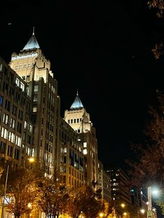 a city street at night with tall buildings in the background