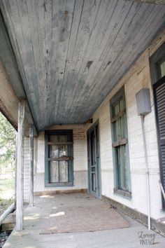 an old house with wood siding and green shutters on the front door, porch