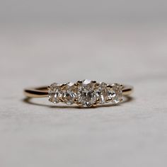 three stone diamond ring sitting on top of a white countertop in front of a gray background