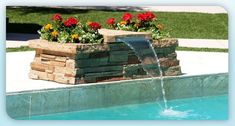 a water fountain with flowers in it next to a swimming pool