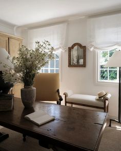 a living room filled with furniture and a wooden table topped with a vase full of flowers