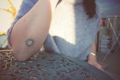 a woman with a sun tattoo on her arm