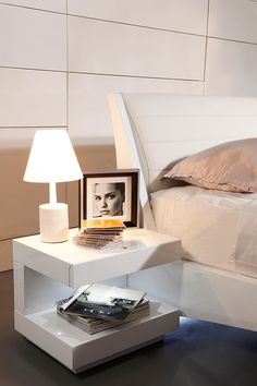 a bedroom with a bed, nightstand and lamp on the side table in front of it