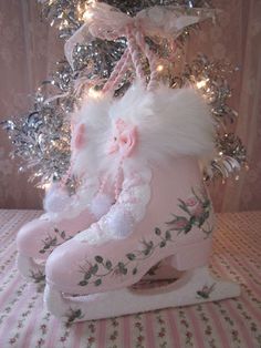 a pair of pink ice skates sitting on top of a table next to a christmas tree