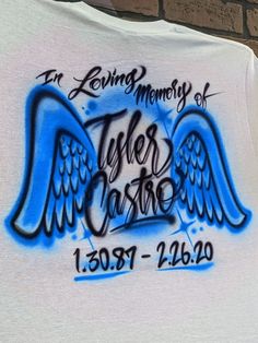 a white shirt with blue wings and the words loving memory of tyler castle on it