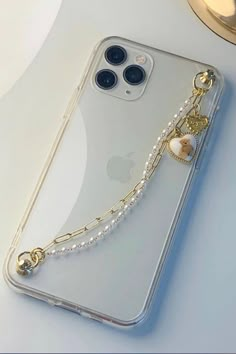 an iphone case with a chain attached to the back and pearls hanging from it's sides