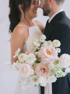 the bride and groom are posing for a wedding photo with their bouquet in front of them