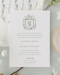 the wedding stationery is laid out on a table with white flowers and greenery