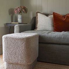 a living room with a couch, chair and vase on the side table in front of it