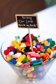 a bowl filled with legos and a sign that says building our love brick by brick