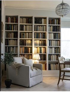 a living room filled with lots of books on top of a white book shelf next to a window