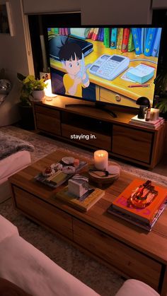 a living room with a television and books on the coffee table in front of it