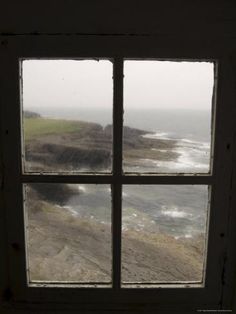 an open window looking out at the ocean and land from it's windowsill