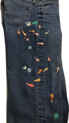 a pair of jeans with fish embroidered on them